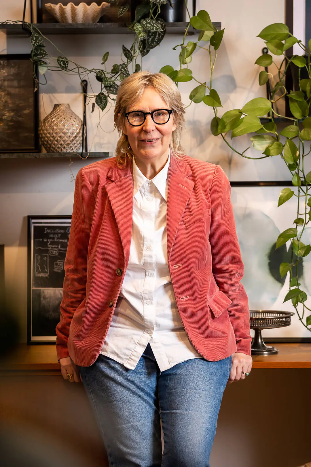 Karin Tenelius i röd kavaj i ett rum med gröna växter